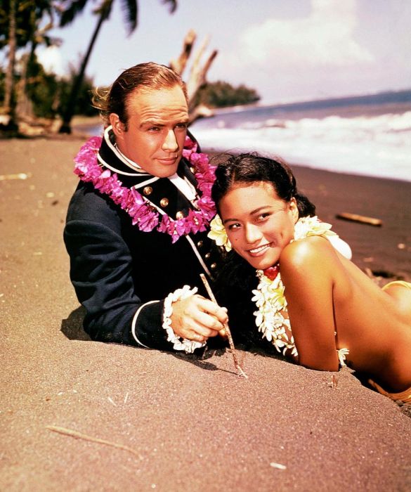 <p>Marlon Brando in una scena de <em>Gli ammutinati del Bounty</em>, insieme alla futura moglie Tarita Teriipia. I due si conobbero sul set e si sposarono l’anno successivo: la coppia ebbe due figli e visse sull’isola di Tetiaroa, di proprietà dell'attore, fino al divorzio avvenuto nel 1972.</p>
