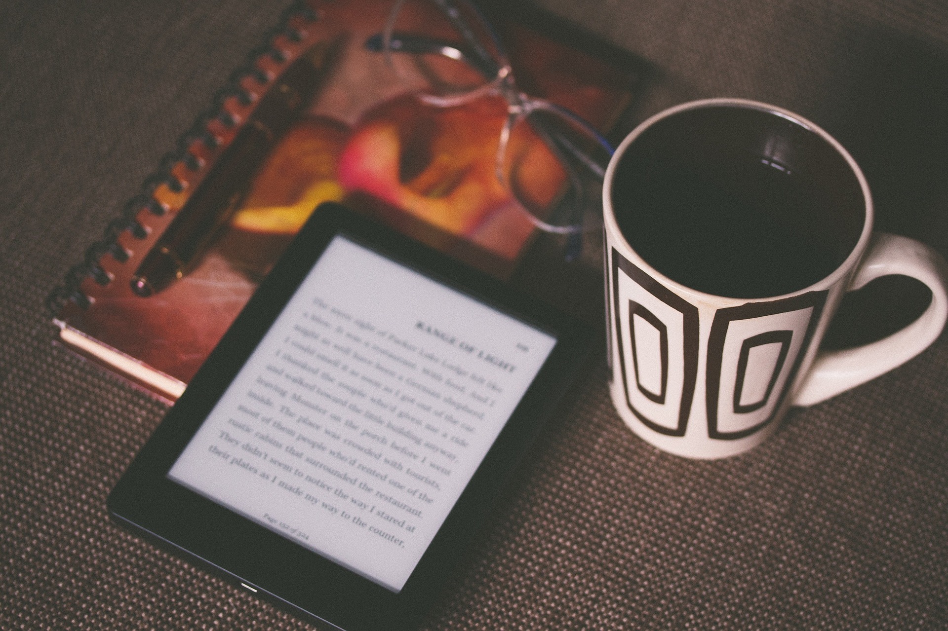 kindle tra una tazza di caffe occhiali e quaderno